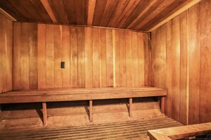 Una sauna de madera con un banco y una pequeña mesa.
