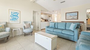 A living room with a blue sofa, two armchairs, a white coffee table, and a ceiling fan.