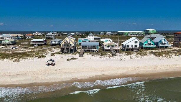 A beachfront property with multiple houses, some elevated on stilts, and a sandy beach.