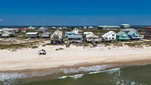 Ein Strandgrundstück mit mehreren Häusern, von denen einige auf Stelzen stehen, und einem Sandstrand.