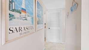 A hallway with framed artwork of a sailboat and the text "SARASOTA FLORIDA". - Seaside Escape – Beach Castle #24 by RVA (Longboat Key)