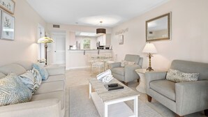A living room with a sofa, armchairs, a coffee table, and a dining area with a table and chairs. - Seaside Escape – Beach Castle #24 by RVA (Longboat Key)