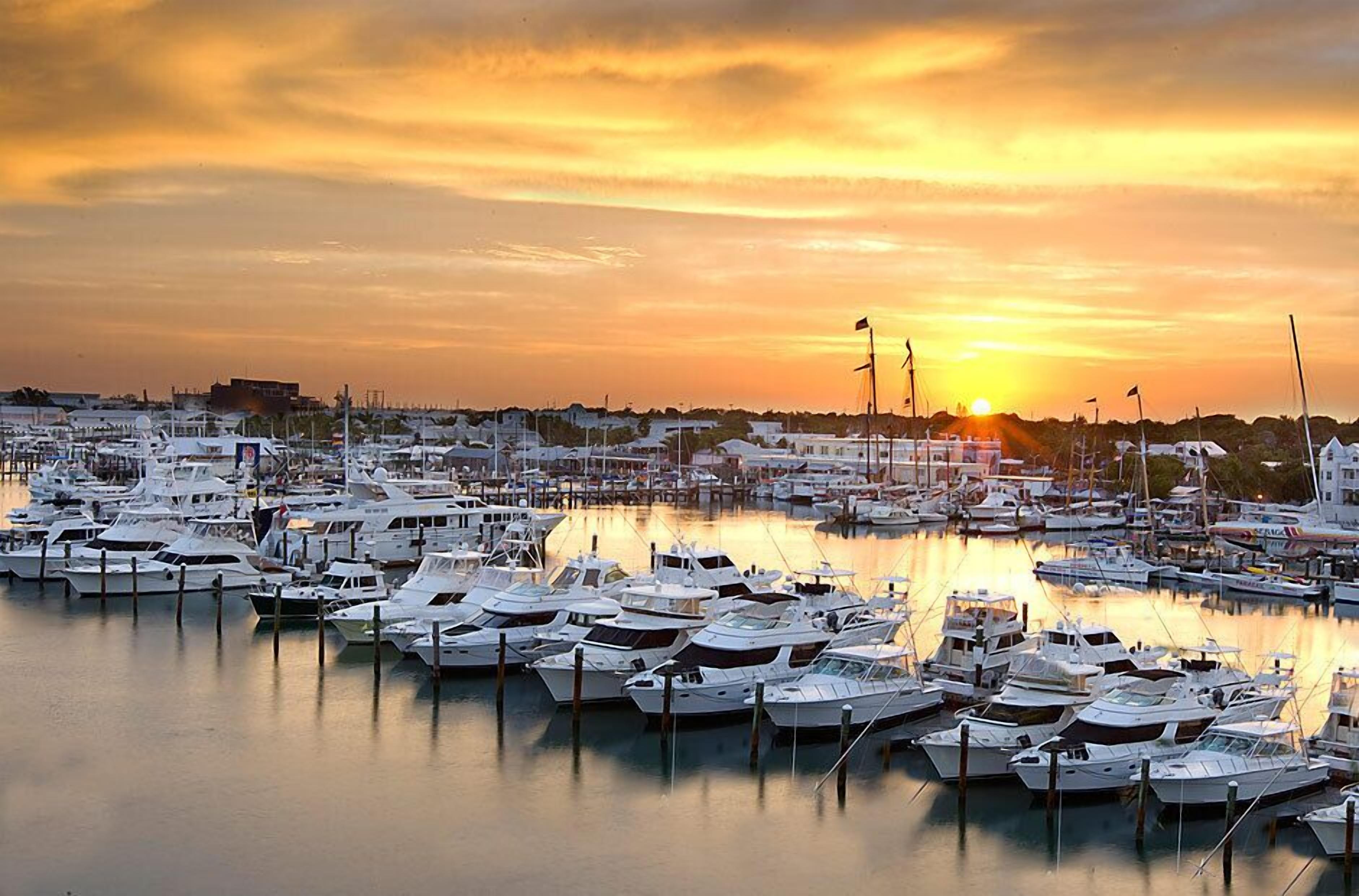 A marina with numerous boats docked at calm waters during sunset.
