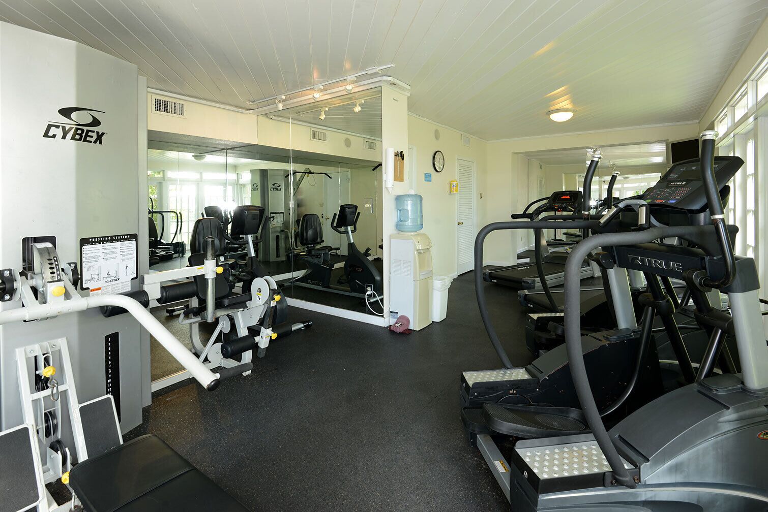 A gym with exercise equipment, a water dispenser, and a mirror.
