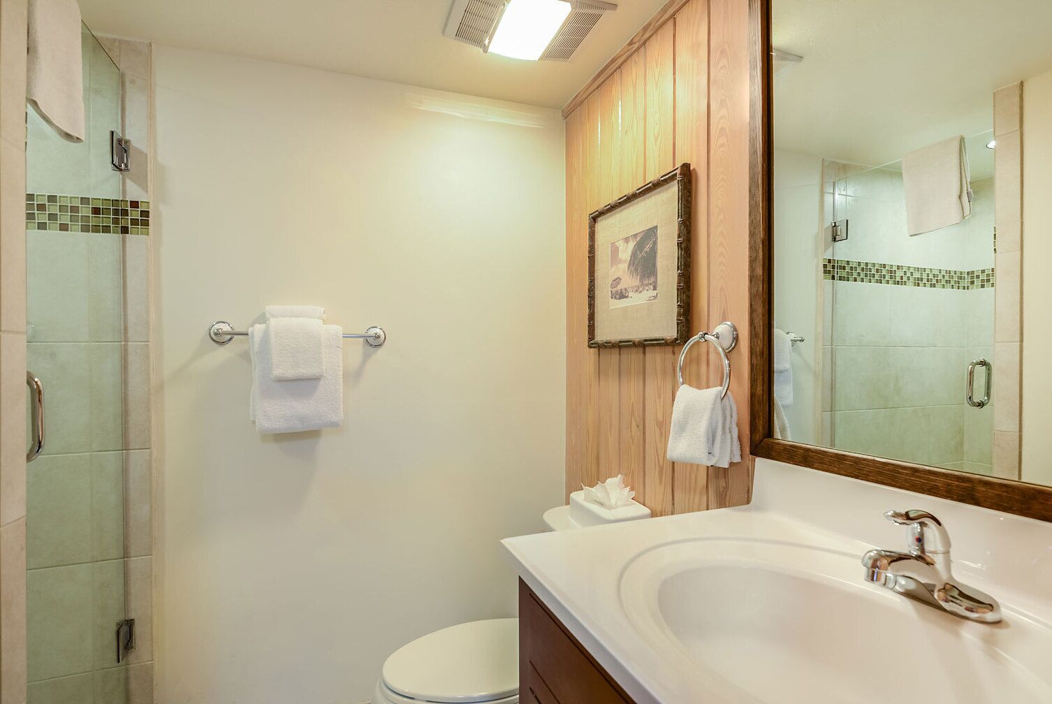 A bathroom with a large mirror, a sink, and a shower area.