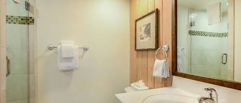 A bathroom with a large mirror, a sink, and a shower area.