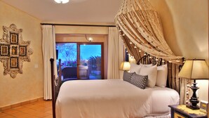 Ein Hotelzimmer mit Bett, Nachttisch, Lampe, Blick ins Freie und einer Wanddekoration.