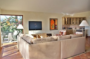A living room with a sofa, television, and artwork on the wall.