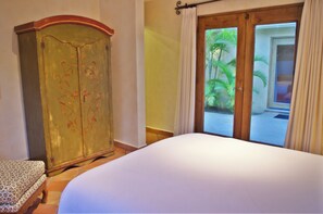 A bedroom with a bed, a wardrobe, and a view of a garden through a door.