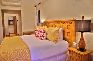 A hotel room with a bed, a bedside table, a lamp, and a wall-mounted air conditioner.
