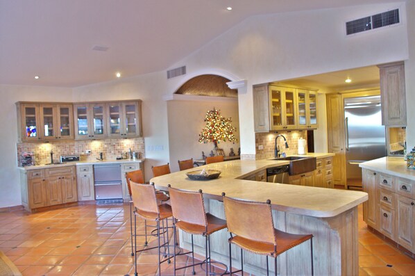 A spacious kitchen with a large island, wooden cabinets, and a stainless steel refrigerator.