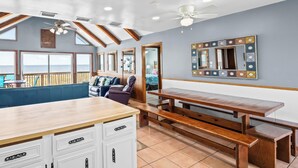 A room with a wooden bench, a dining table, a sofa, and a ceiling fan. - Mitts-issippi - Charming 4br/2ba Gulf Front Home, Sleeps 10 (Gulf Shores)