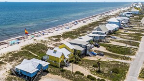 A coastal hotel with multiple buildings, a beach, and a sailboat. - Mitts-issippi - Charming 4br/2ba Gulf Front Home, Sleeps 10 (Gulf Shores)