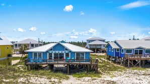 A beachfront property with multiple houses, some elevated on stilts, and a sandy beach in the foreground. - Mitts-issippi - Charming 4br/2ba Gulf Front Home, Sleeps 10 (Gulf Shores)