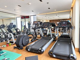 Un gimnasio con cintas de correr, elípticas y pesas libres.