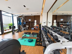A gym with exercise equipment, a mirror, and a view of the outdoors. - HANSA - A Premium Residence (Dhaka)