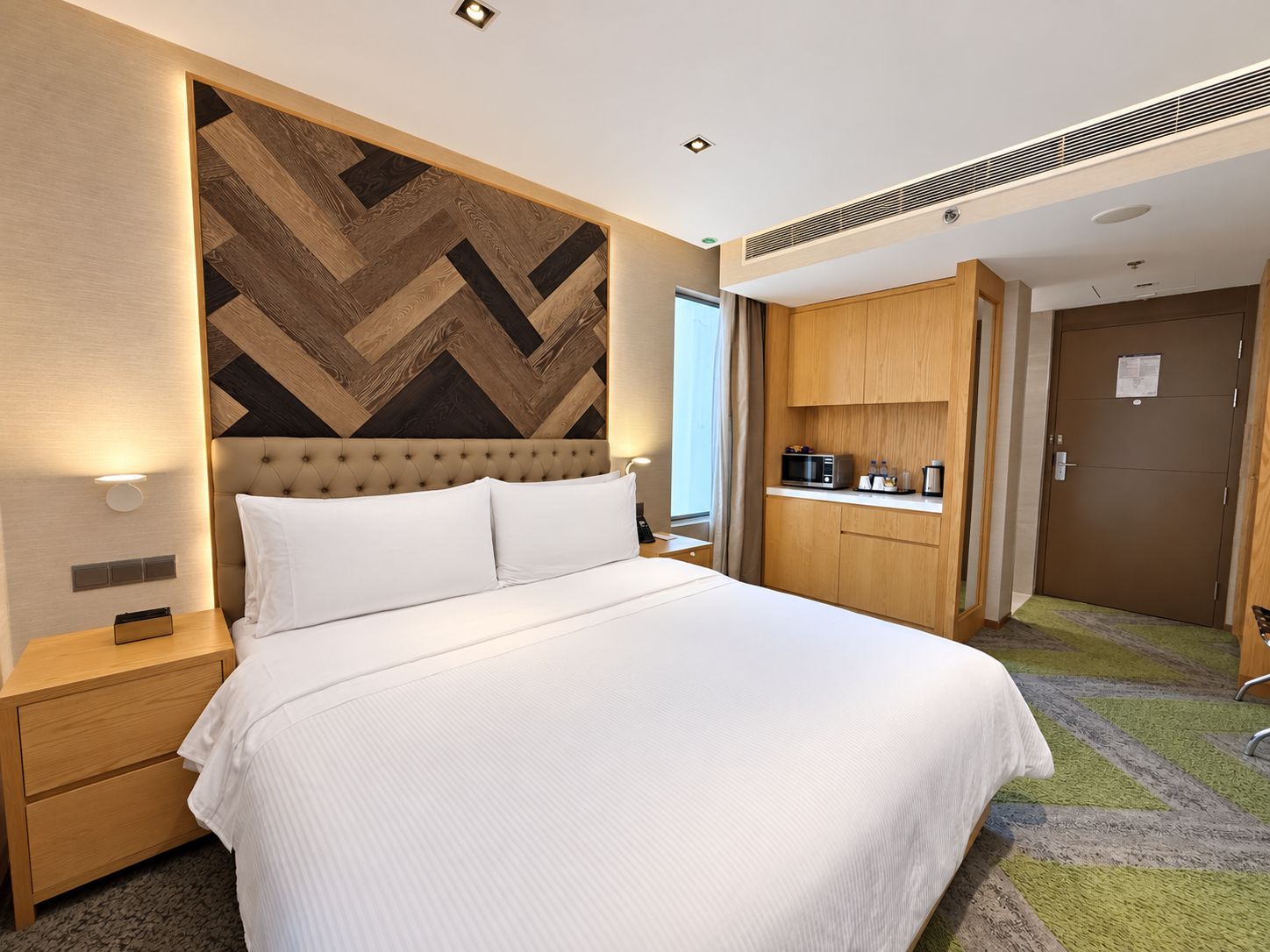 Une chambre d’hôtel comprenant un lit, une table de chevet, une armoire intégrée, un four à micro-ondes et une porte.