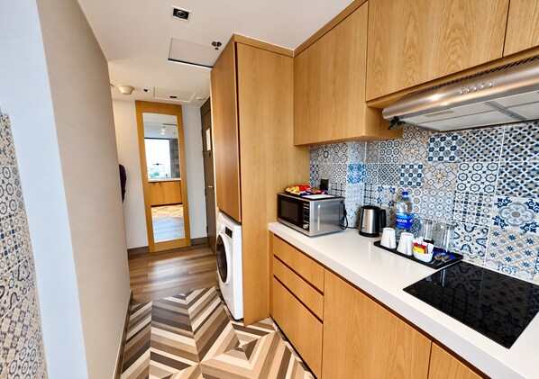 A compact kitchen with wooden cabinets, a microwave, a kettle, and a water dispenser. - HANSA - A Premium Residence (Dhaka)
