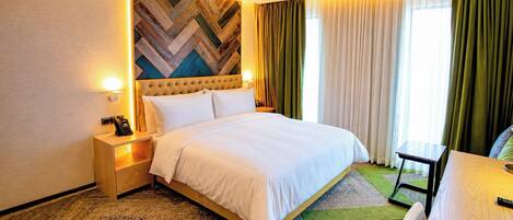 A hotel room with a bed, bedside tables, a telephone, a lamp, a small table, and a chair.