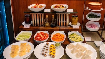 A buffet with various food options including salads, sushi, and sandwiches.