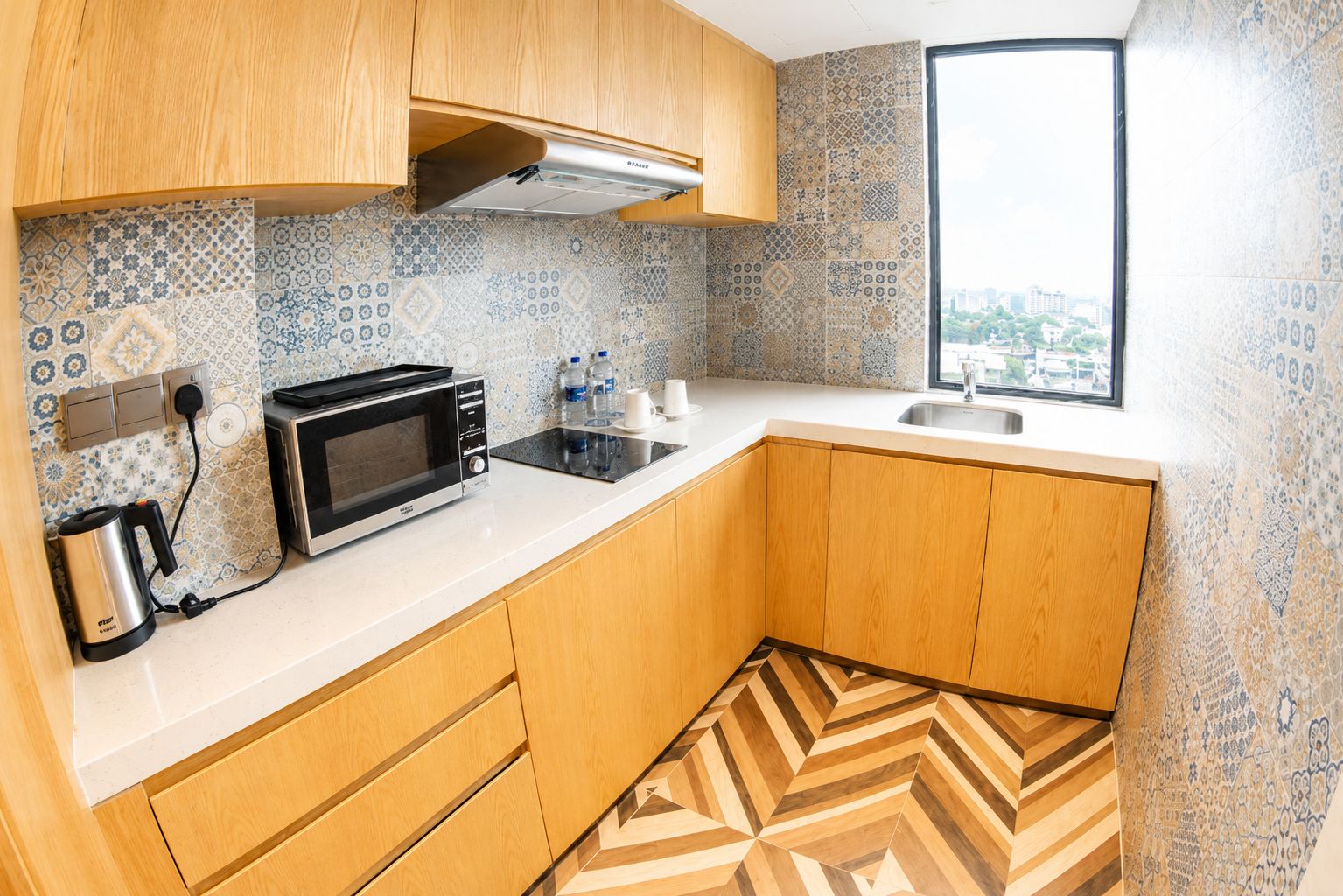 Cocina compacta con microondas, hervidor y botellas de agua sobre la encimera.