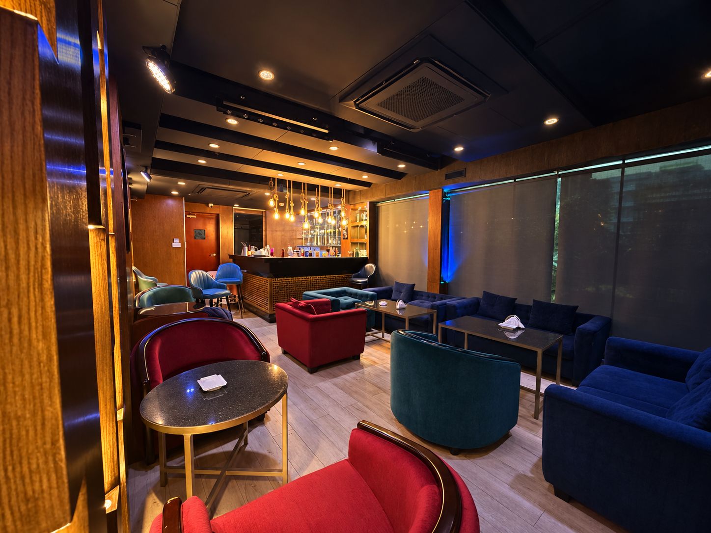 A modern lounge area with seating arrangements, a bar, and a large window providing a view.