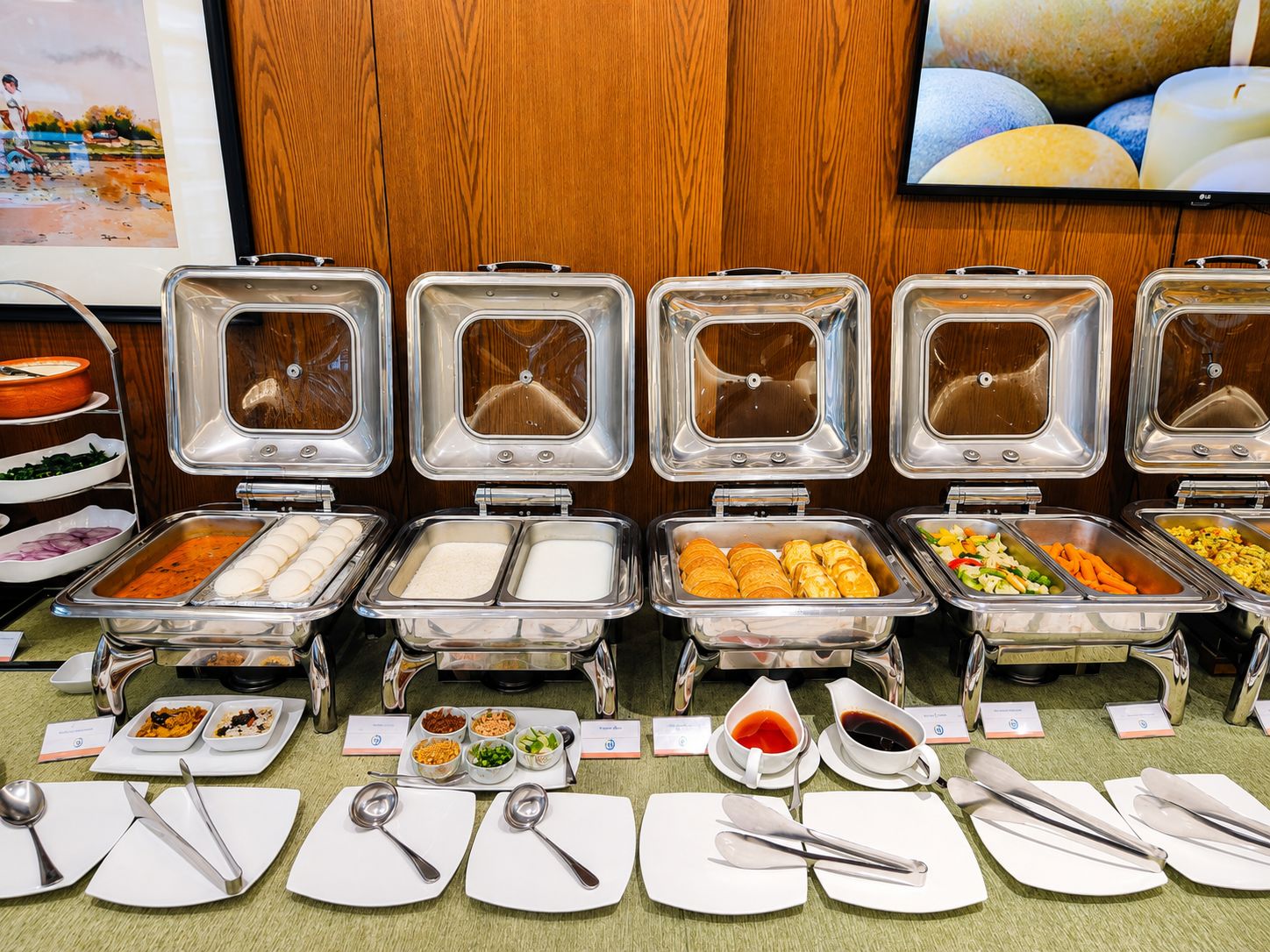 A buffet setup with various food items and utensils.