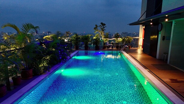 A swimming pool with a view of the city at dusk. - HANSA - A Premium Residence (Dhaka)