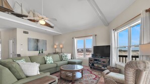 A living room with a green sofa, a round coffee table, a wicker chair, a TV, and a large window with a view. - Gorgeous 4 Bdrm, 3 Ba Gulf Front Private Home, Sleeps 10 (Gulf Shores)