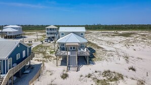 A beachfront property with multiple buildings, including a large house with a covered porch and a smaller structure with a balcony. - Gorgeous 4 Bdrm, 3 Ba Gulf Front Private Home, Sleeps 10 (Gulf Shores)