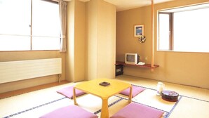 A traditional Japanese room with tatami flooring, a low table with cushions, a television, and a radiator. - Hotel Chalet-Ryuo (Yamanouchi)
