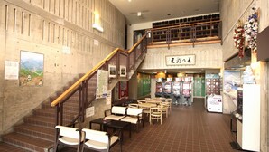A spacious indoor area with a staircase leading to an upper level, multiple seating areas, and a vending machine. - Hotel Chalet-Ryuo (Yamanouchi)