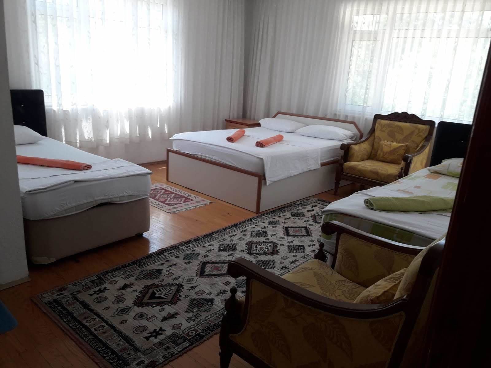 Une chambre d’hôtel avec deux lits, un canapé, un fauteuil et un tapis à motifs.