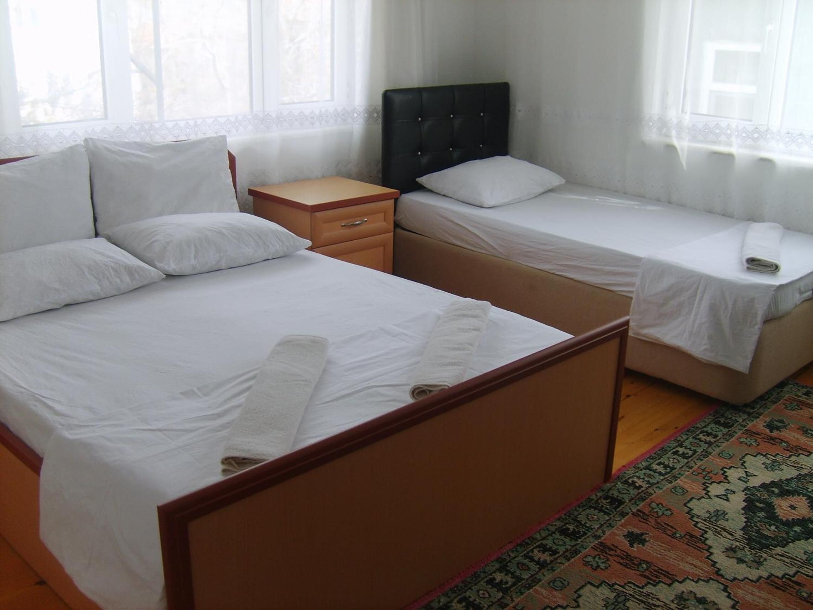 A hotel room with a large bed, a smaller bed, a nightstand, and a window with a view.