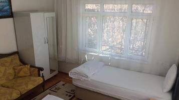 Una habitación con cama, sofá, armario y ventana con vistas a árboles.