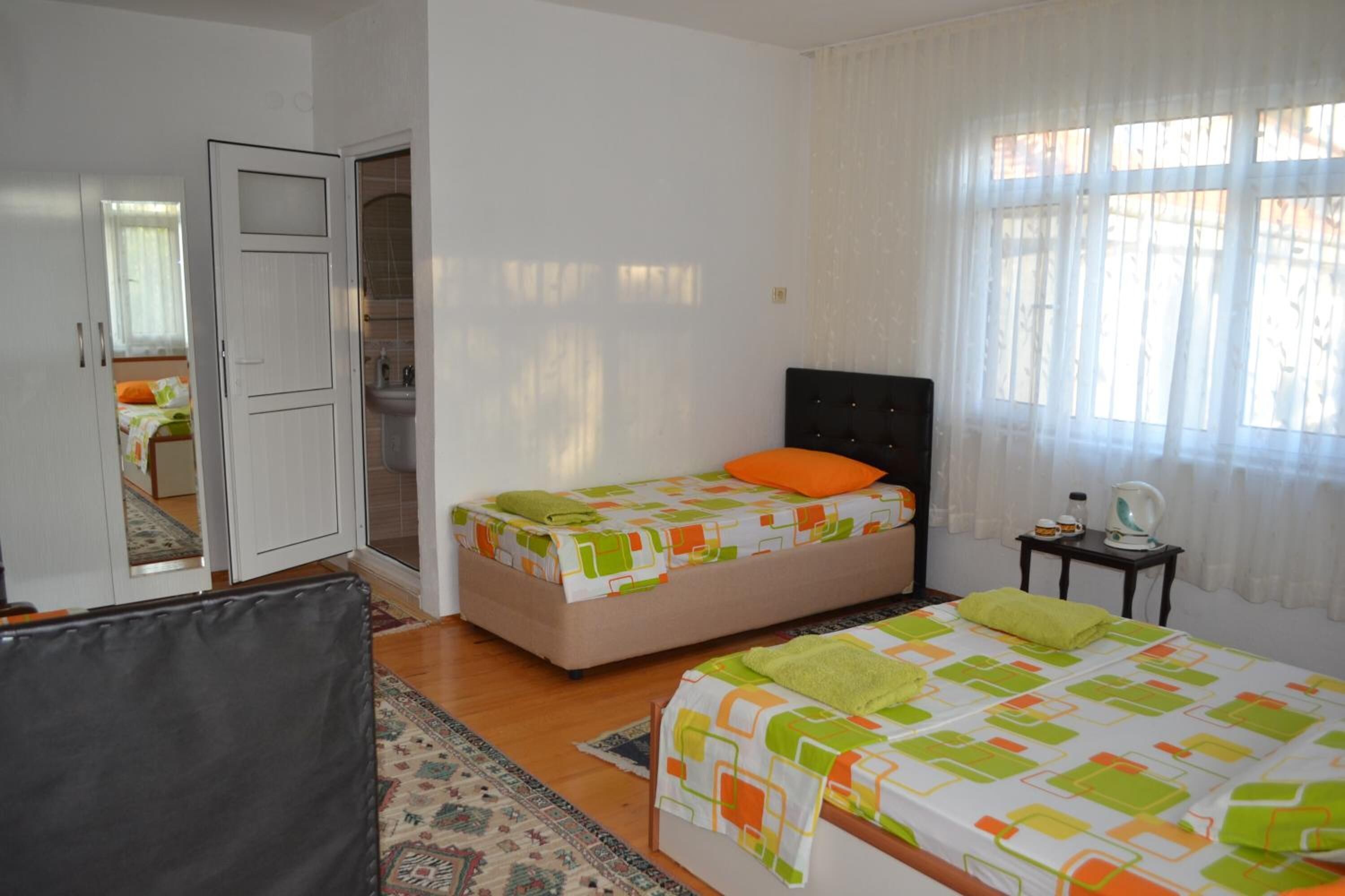 Un dormitorio con dos camas, un baño y una puerta visible que da a otra habitación.