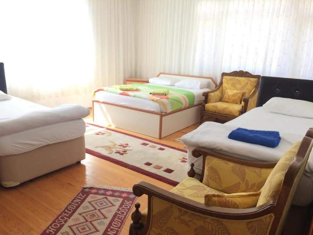A hotel room with a bed, two armchairs, a sofa, and a wooden floor.