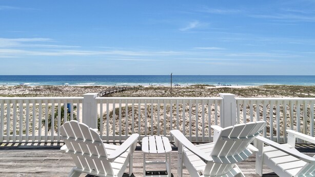 A wooden deck with white Adirondack chairs and a small table, overlooking a beach with a wooden walkway and beachgoers. - Luxury 6 Bdrm/6 Ba Gulf Front w/Private Pool and Great Views (Gulf Shores)