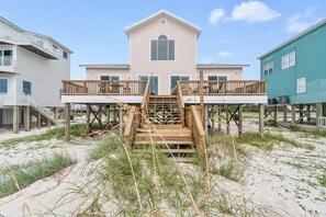 Une maison située en bord de mer, avec un escalier en bois menant à une terrasse.