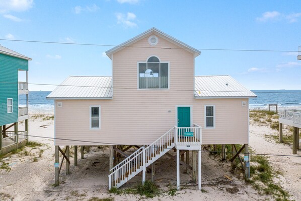 A two-story beach house with a staircase leading to the entrance, situated on stilts over the sand. - Gulf Front, Beautiful 3 Bedroom Plus Loft Private Home, Sleeps 10- Tamaron (Gulf Shores)