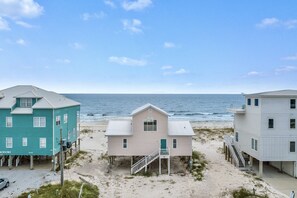 Une propriété située en bord de mer, composée de trois bâtiments, chacun doté d’un balcon et d’un escalier menant à la plage.