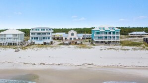 Een vakantiehuis aan het strand met meerdere woningen, waarvan sommige balkons hebben en andere terrassen, met uitzicht op de oceaan.