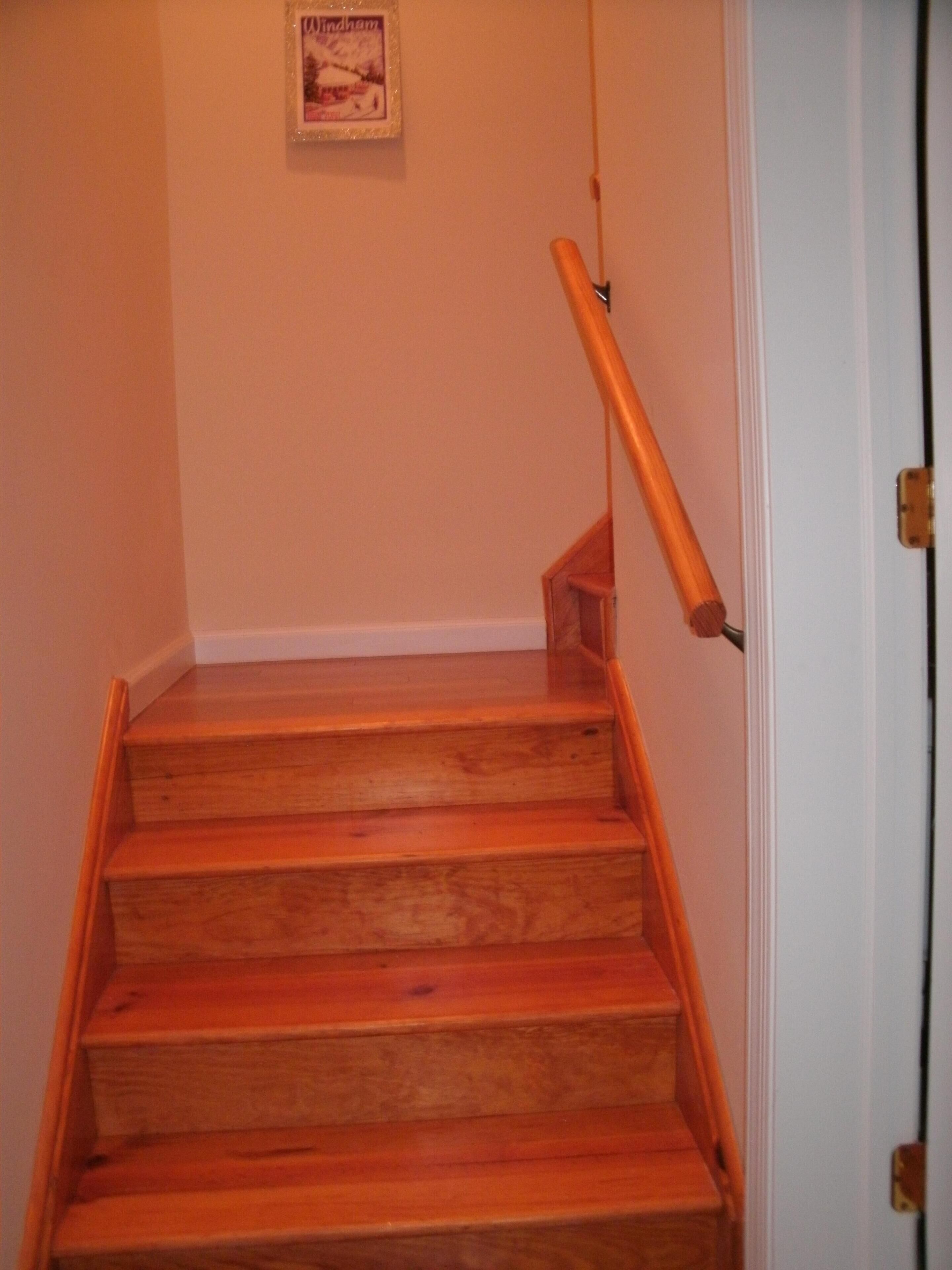 Eine Holztreppe mit Handlauf führt zu einer weißen Tür.