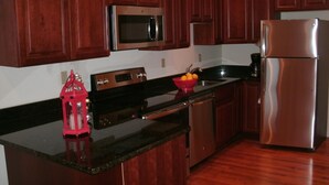 A kitchen with wooden cabinets, stainless steel appliances, a red lantern, and a fruit bowl on the counter. - TOWNHOUSE-Slp 8 Mt View/6 BEDS. Downtown Windham. Walk to restaurants and stores (Windham)