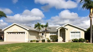 A two-story house with a garage, a covered porch, and a well-maintained lawn. - Surfside Area Vacation Home Awaits (Cape Coral)