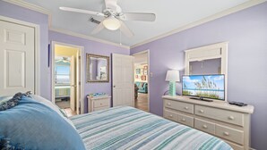 Ein Schlafzimmer mit Bett, Kommode, Fernseher und Deckenventilator.