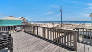 Eine Holzterrasse mit Blick auf Strand und Meer.