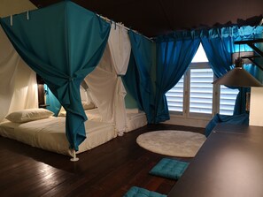 Un dormitorio con cama con dosel, un tapete redondo y un escritorio con lámpara.