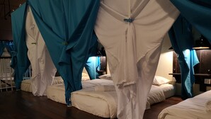 Una habitación con cuatro camas, cada una con ropa blanca y dosel azul.