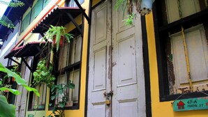 A building with a yellow facade, a white door, and a green sign indicating "47-A Muntri St."